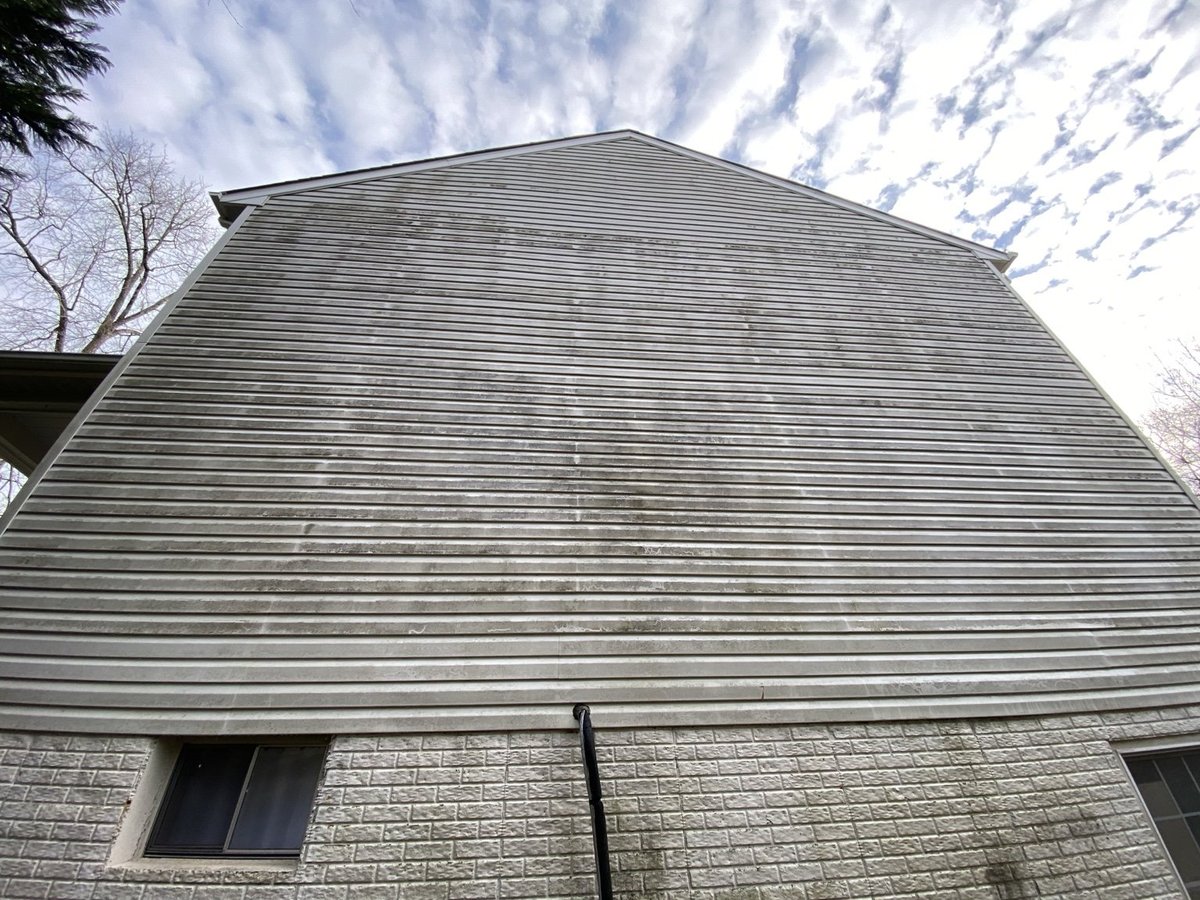 Modern building with gray corrugated metal siding and brick foundation against cloudy sky